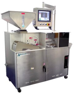 Large, stainless steel industrial machine with a touchscreen control panel, labeled “Ackley Hartnett.” It features a hopper, viewing window, and several buttons and controls, all on caster wheels for mobility.