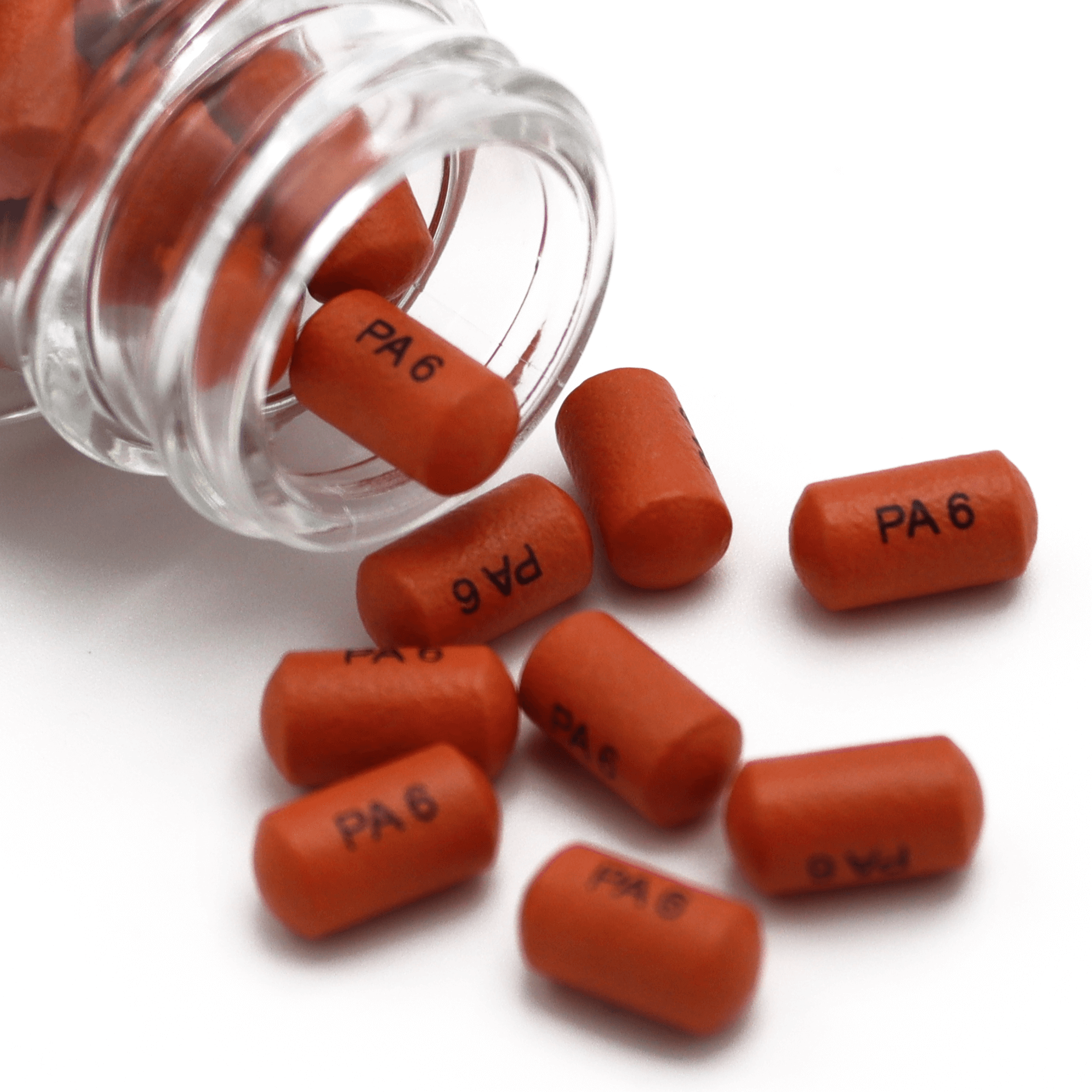 A clear bottle tipped over, spilling several small, cylindrical, dark orange tablets labeled "PA 6" with crisp capsule printing onto a white surface.